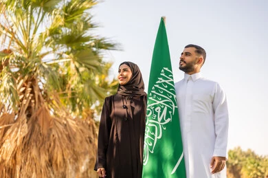 رجل وامرأة سعوديان مع العلم الوطني في الخارج