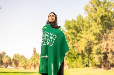 امرأة سعودية مع العلم الوطني في الحديقة