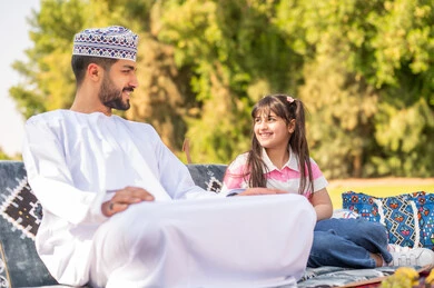 رجل عماني وفتاة بالزي التقليدي في الهواء الطلق