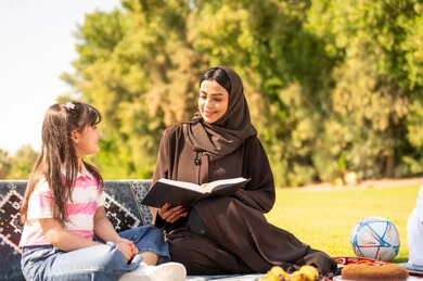 أم سعودية وابنتها تقرآن كتاباً في نزهة بالحديقة