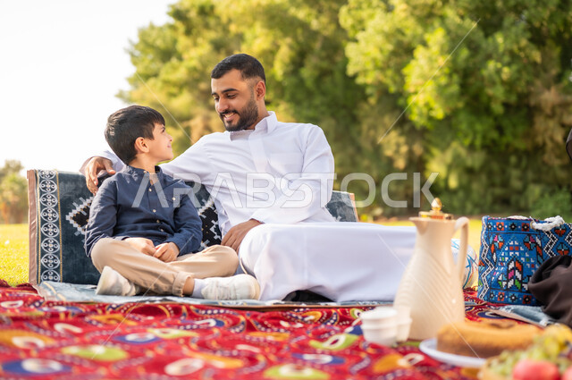 رجل سعودي وطفل بالزي التقليدي في نزهة بالحديقة