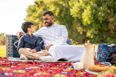 رجل سعودي وطفل بالزي التقليدي في نزهة بالحديقة