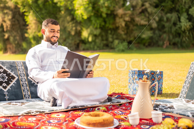 رجل سعودي يقرأ كتاباً في نزهة بالحديقة