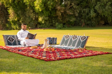 Saudi Man in Traditional Thobe Reading in Park Saudi Man in Traditional Thobe Reading in Park
