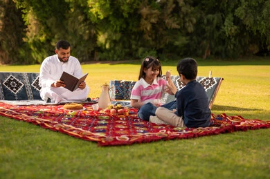 Saudi Family Picnic in Green Park with Traditional Rug Saudi Family Picnic in Green Park with Traditional Rug