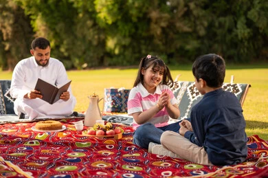 Saudi Father and Children Having a Picnic in the Park Saudi Father and Children Having a Picnic in the Park