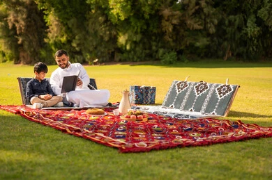 أب سعودي يقرأ مع ابنه خلال نزهة عائلية في الحديقة