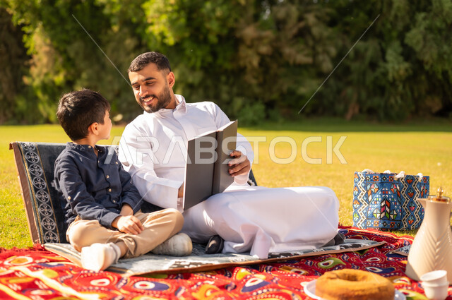 أب سعودي يقرأ كتاباً لابنه في حديقة خارجية