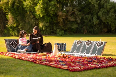 أم سعودية تقرأ لابنتها في الحديقة