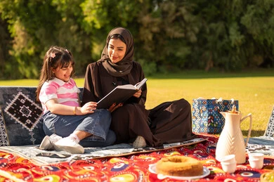 Saudi Mother and Daughter Reading Book at Park Picnic Saudi Mother and Daughter Reading Book at Park Picnic