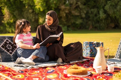 أم وابنتها تقرآن كتاباً في نزهة بالحديقة أم وابنتها تقرآن كتاباً في نزهة بالحديقة