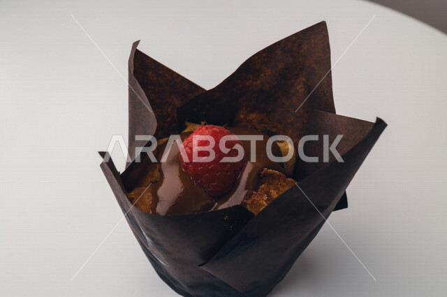 صورة لكعكة الشوكولاتة مزينة بالتوت الاحمر وصوص الشوكولاة ، كب كيك ، حلوى مخبوزة 