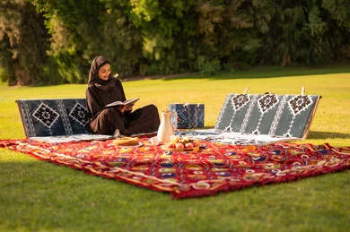 امرأة إماراتية تقرأ كتاباً في نزهة تقليدية بالحديقة