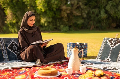 Saudi Woman Reading Book at Traditional Outdoor Picnic Saudi Woman Reading Book at Traditional Outdoor Picnic