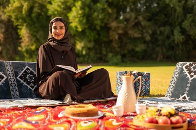 Emirati Woman Reading Book in Traditional Outdoor Setting