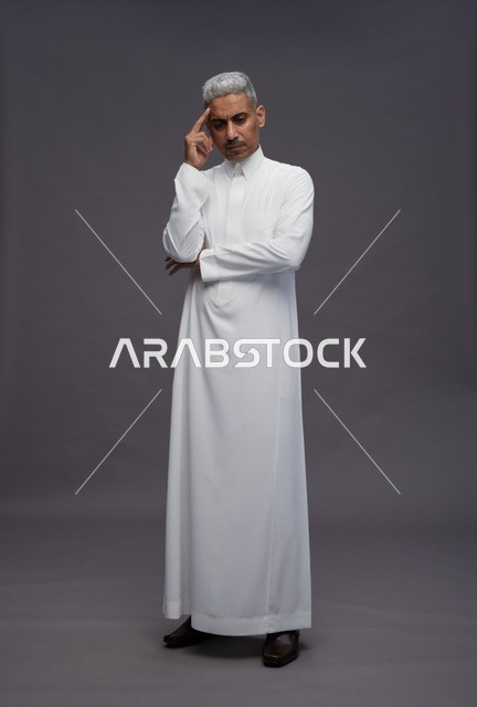 رجل سعودي بالثوب الأبيض بوضعية تفكير خلفية رمادية