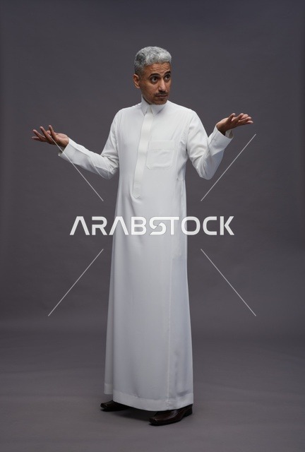 رجل سعودي بالثوب الأبيض يرفع يديه بتعبير متسائل