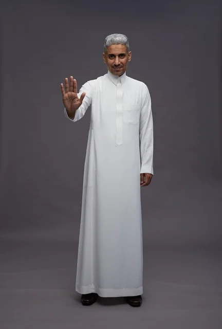 رجل سعودي بالثوب التقليدي يقوم بإيماءة التوقف