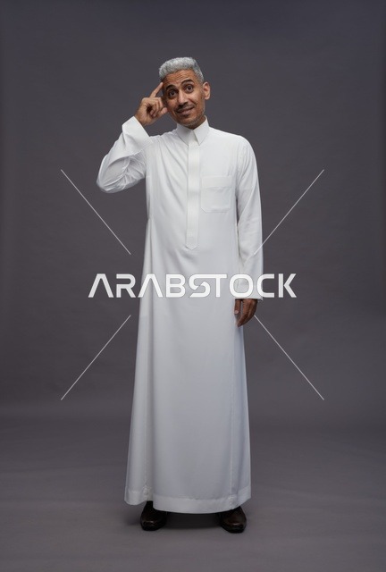 رجل سعودي يرتدي الثوب التقليدي يفكر بخلفية رمادية