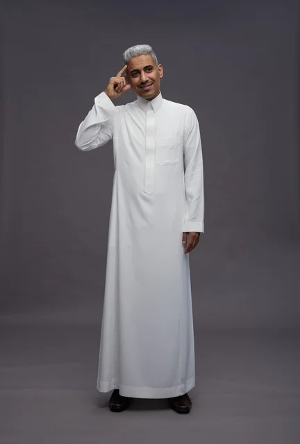 رجل سعودي بالثوب الأبيض يشير برأسه بخلفية رمادية
