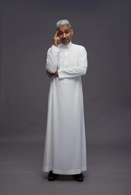 رجل سعودي بالثوب الأبيض يفكر أمام خلفية رمادية
