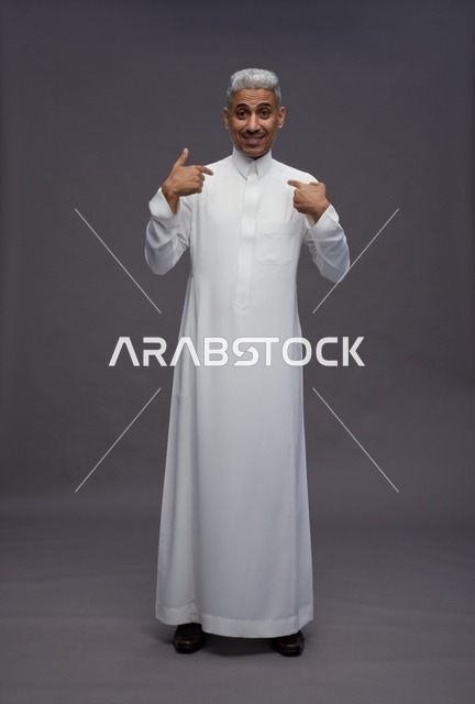 رجل سعودي بالثوب الأبيض التقليدي يشير إلى نفسه