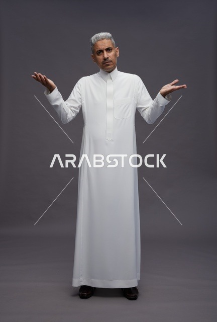 رجل سعودي بالثوب الأبيض يرفع يديه بحيرة