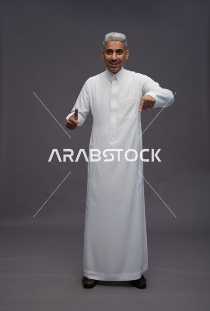 Saudi Man in White Thobe Pointing Down on Grey Background
