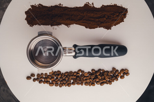 صورة مقربة لذراع ماكينة الاسبريسو بين مجموعة من حبوب البن و القهوة المطحونة ، اعداد كوب الاسبريسو ، صنع القهوة ، المشروبات الساخنة 