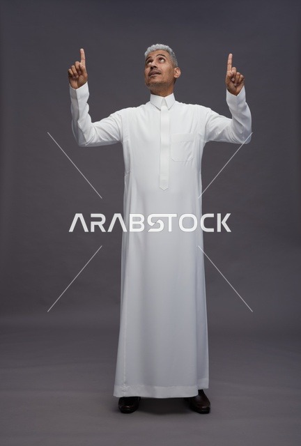 Saudi Man in Thobe Pointing Up on Gray Background