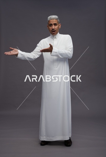 رجل سعودي بالثوب يشير لشيء خلفية رمادية