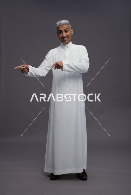 Saudi Man in Thobe Pointing at Grey Background