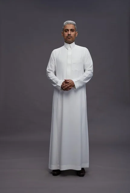 رجل سعودي بالثوب الأبيض التقليدي على خلفية رمادية