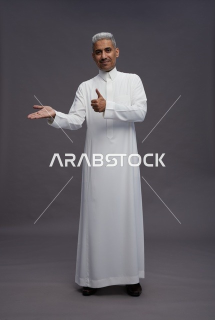 Saudi Man in Traditional Thobe Pointing and Thumbs Up