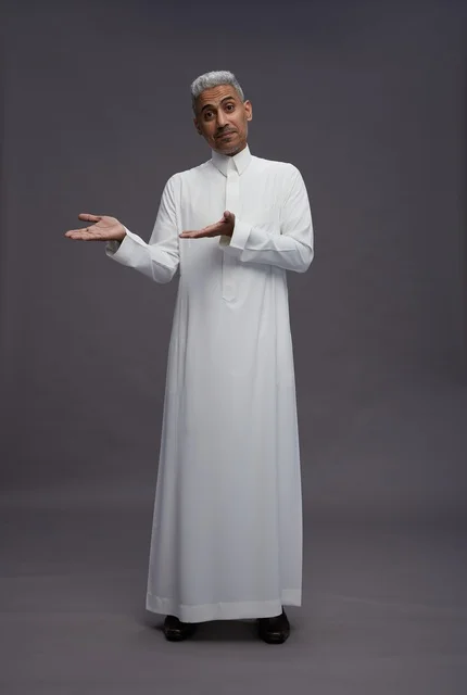 رجل سعودي بالثوب الأبيض يشير بيديه خلفية رمادية