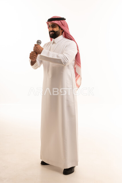 رجل سعودي يمسك ميكروفون في استوديو أبيض