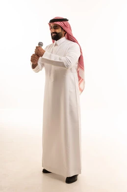 رجل سعودي يمسك ميكروفون في استوديو أبيض