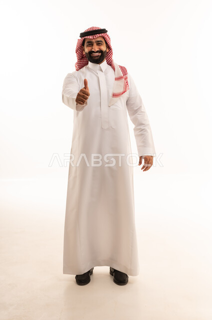 رجل سعودي بالزي التقليدي يشير بعلامة الإعجاب