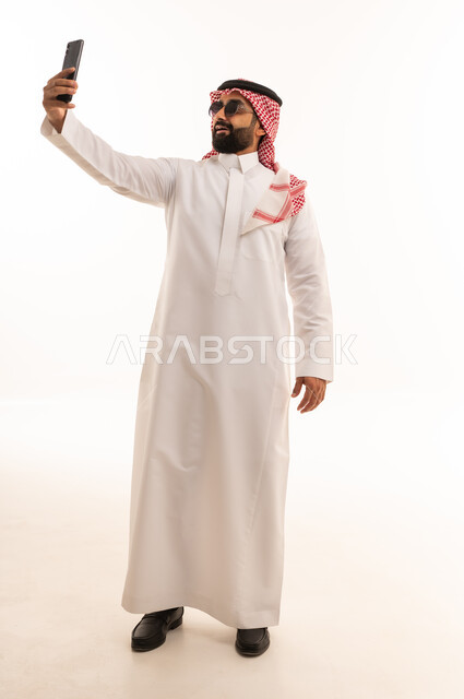 رجل سعودي بالزي التقليدي يلتقط سيلفي بالهاتف الذكي