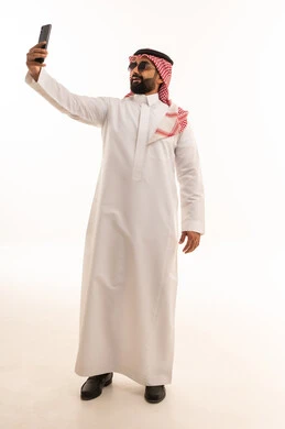 رجل سعودي بالزي التقليدي يلتقط سيلفي بالهاتف الذكي