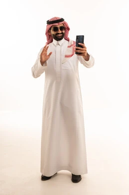 رجل سعودي بالثوب يلوح للهاتف الذكي