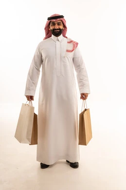 رجل سعودي يحمل حقائب تسوق على خلفية بيضاء