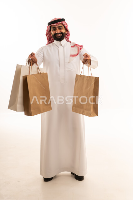 رجل سعودي يحمل حقائب تسوق على خلفية بيضاء