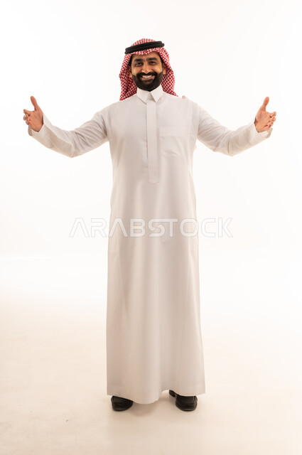 رجل سعودي مبتسم بذراعين مفتوحتين أمام خلفية بيضاء