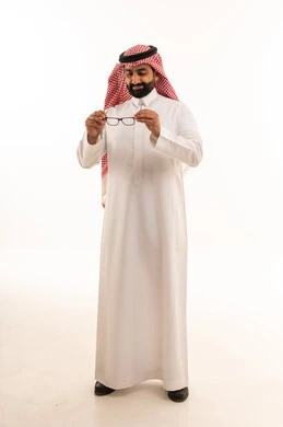رجل سعودي بالثوب التقليدي يحمل نظارة طبية خلفية بيضاء