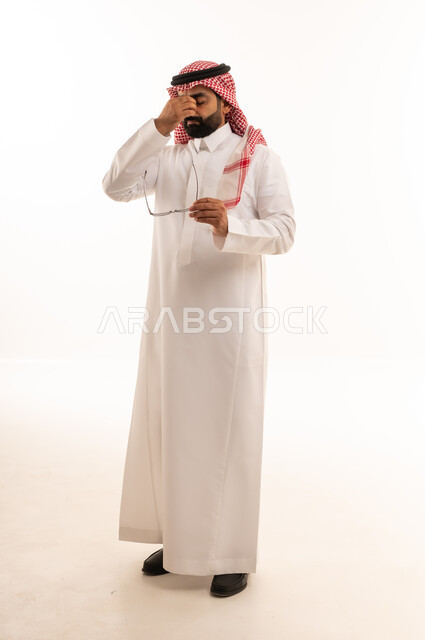 رجل سعودي بالثوب يمسح عينيه من الإجهاد