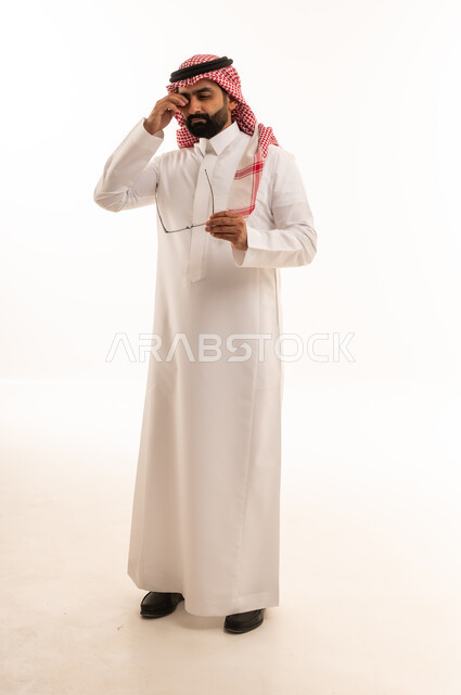 رجل سعودي متعب يفرك عينيه على خلفية بيضاء