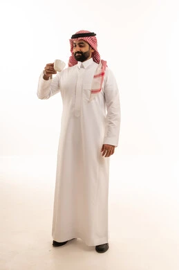 رجل سعودي بالثوب التقليدي يمسك فنجان قهوة