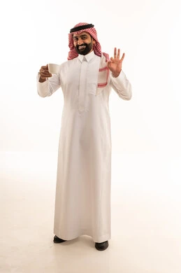 رجل سعودي بالثوب التقليدي يمسك فنجان قهوة في استوديو