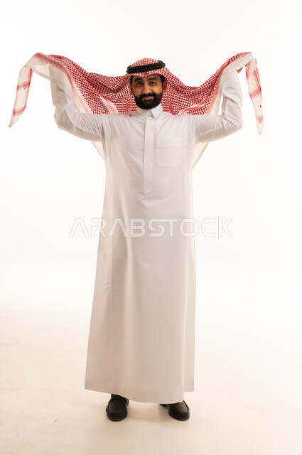 رجل سعودي بالثوب الأبيض يعدل الشماغ الأحمر